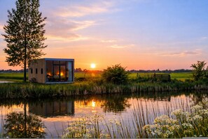 A modern glass house by a calm river at sunset. - Geau Tiny House in Weidum (Weidum)