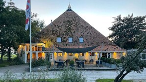 A building with a conical roof, outdoor seating area, and a flagpole. - Geau Tiny House in Weidum (Weidum)