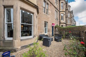 A building with large windows and a patio area with outdoor furniture. - Relax in this stylish flat in the lovely Marchmont area, walk to city centre (Edinburgh)