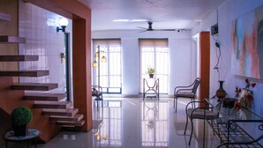 A spacious, well-lit living area with a staircase, seating, and a glass table. - Hotel Posada del Ángel (Mérida)
