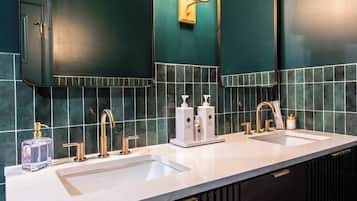 A modern bathroom with two sinks, gold faucets, and a mirror above each.