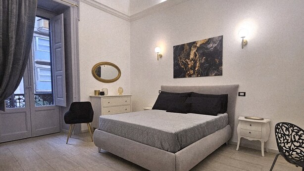 Ein modernes Schlafzimmer mit einem Bett, einem Schminktisch, einem Sessel und einem Bild an der Wand.