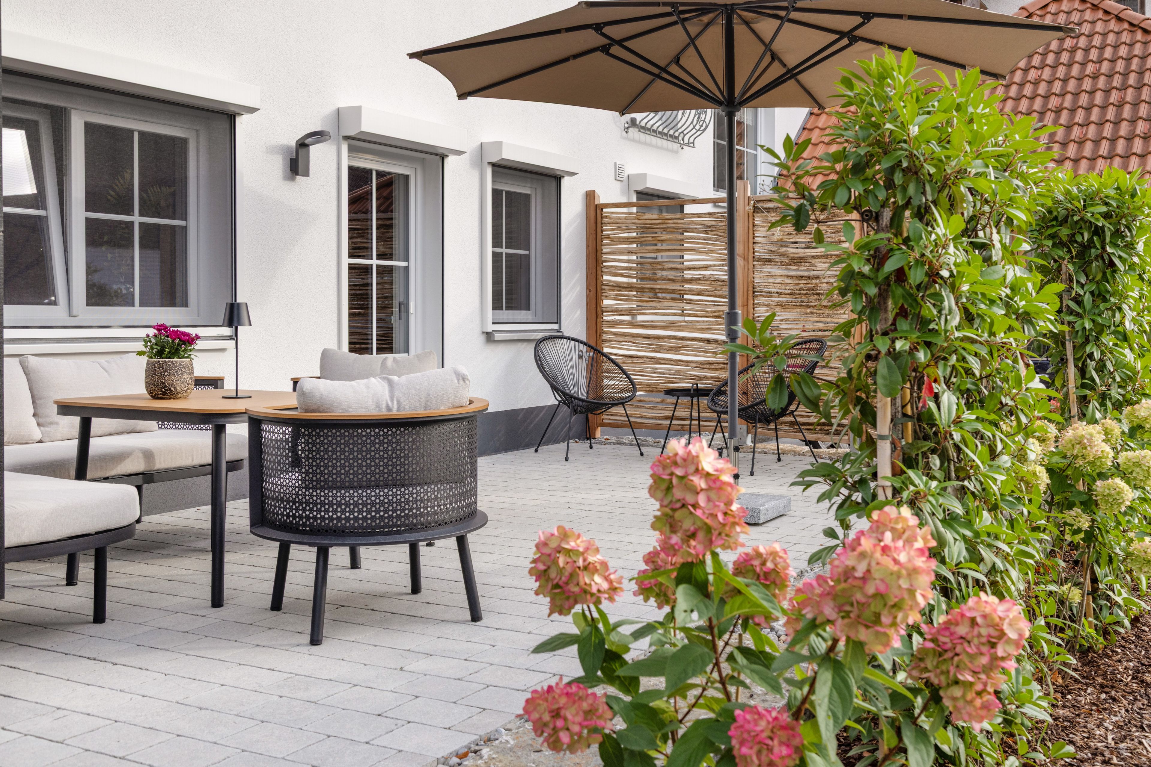 Een terras met een tafel, stoelen en een parasol.