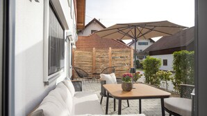 Une terrasse avec un canapé, des chaises, une table et des parasols.