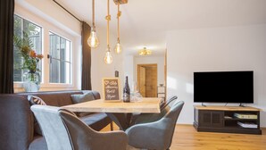 Un salon moderne comprenant un coin repas, un téléviseur à écran plat et une grande fenêtre.