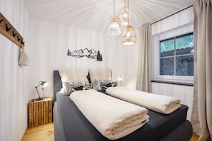 Une chambre à coucher avec un lit, des lampes de chevet, une fenêtre donnant sur un beau paysage et une œuvre d’art accrochée au mur.