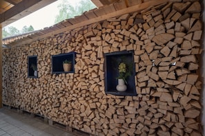 Un mur fait d’une pile de bois de chauffage, percé de trois petites fenêtres, chacune contenant une plante.