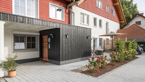 Une maison moderne dotée d’un patio couvert, d’une terrasse en bois et d’un jardin fleuri.