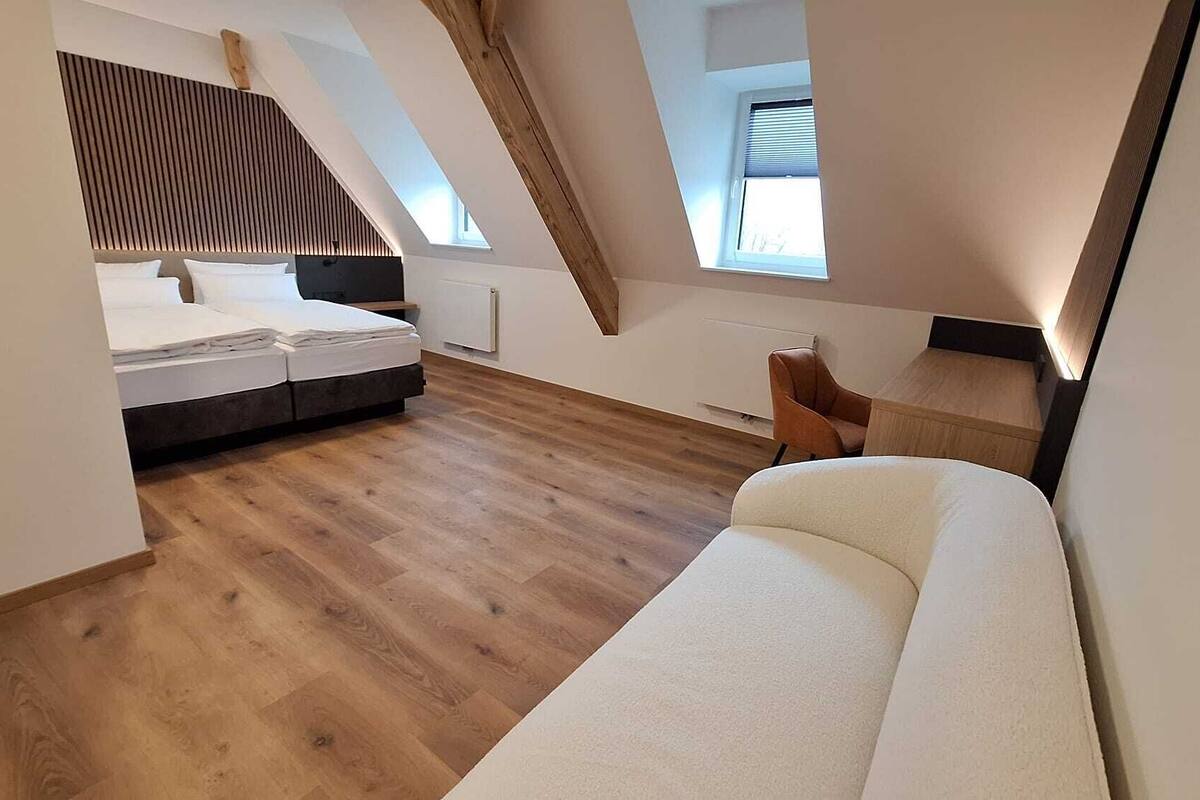 Une chambre de style loft moderne, avec un lit en mezzanine, un canapé, une petite table et une fenêtre.