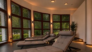 Una sala spa con diverse poltrone reclinabili, ampie finestre con tende e una pianta in vaso.