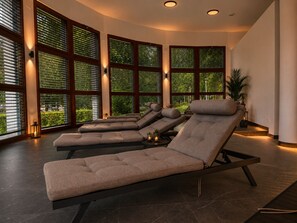 A spa room with multiple reclining chairs, large windows with blinds, and a potted plant. - Pawlow Hotel (Wolkenstein)
