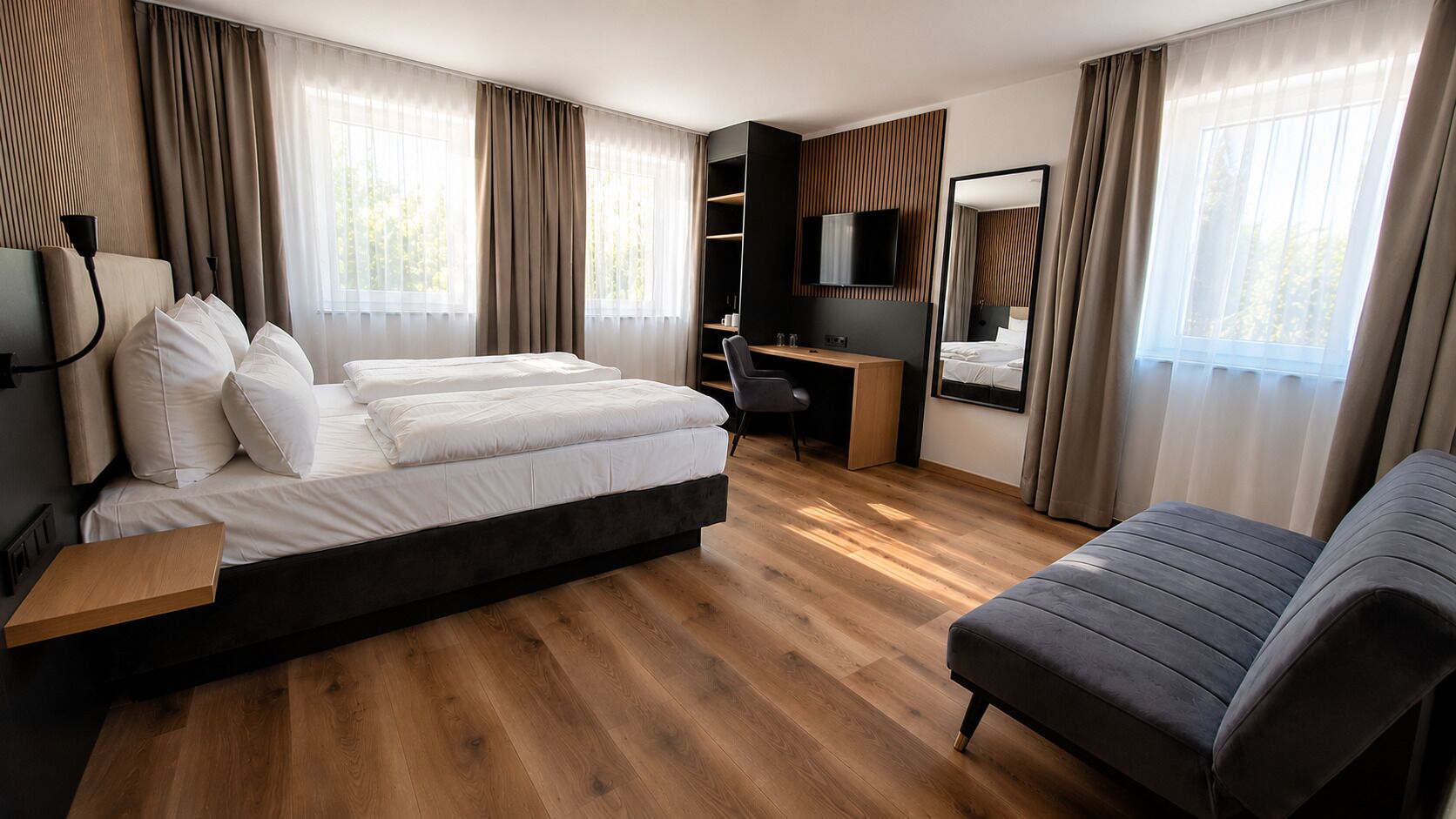 Una habitación de hotel con cama, escritorio, silla, sofá y televisión.