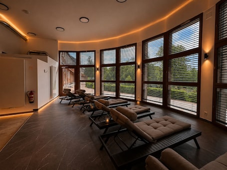A spa room with large windows, reclining chairs, and a fire extinguisher.. Pawlow Hotel