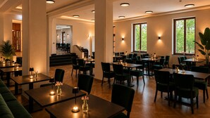Un'ampia sala ristorante con diverse zone pranzo, ampie finestre e una scalinata centrale.