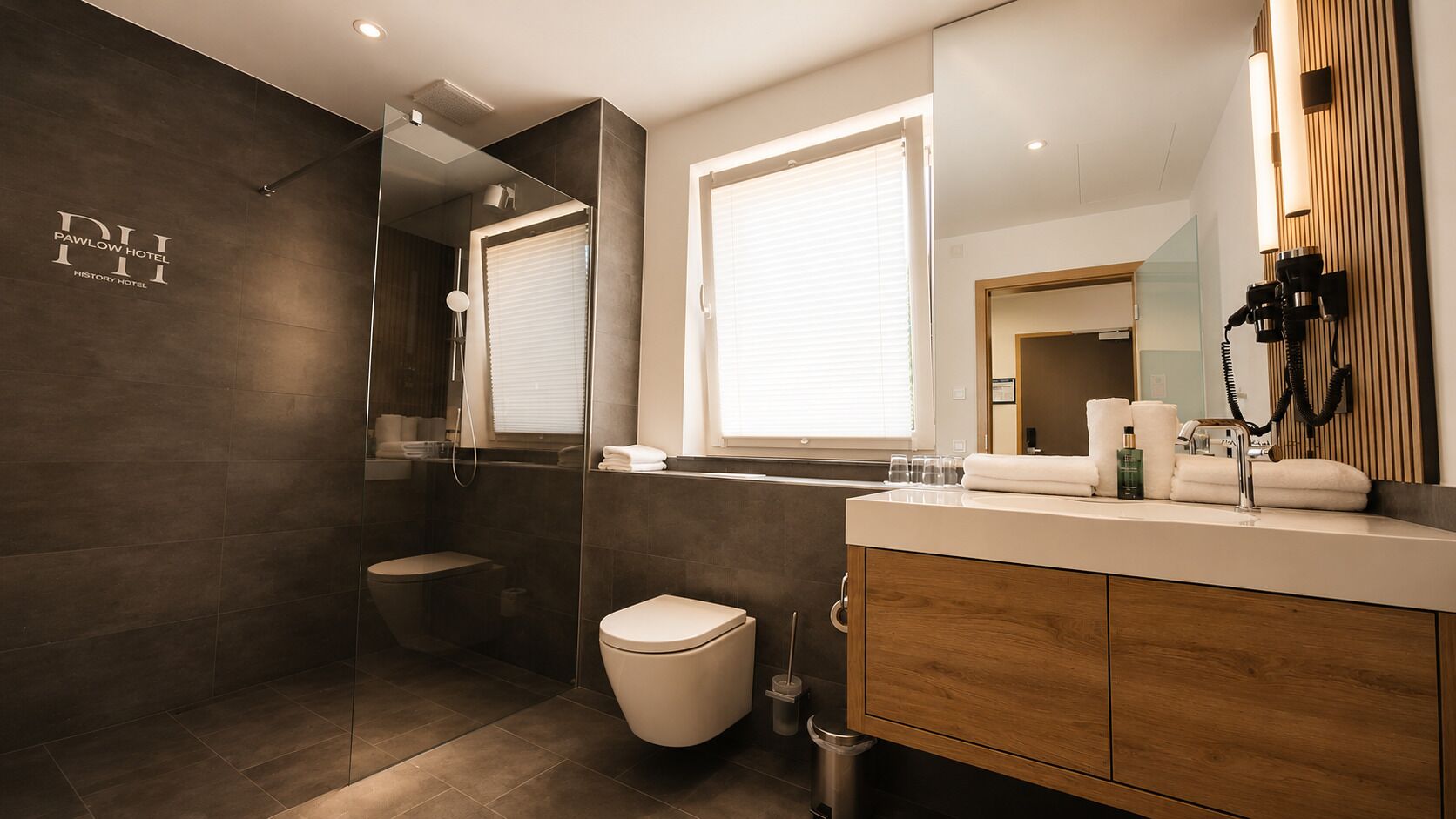 Een moderne badkamer met een inloopdouche, toilet en een wastafel met spiegel.