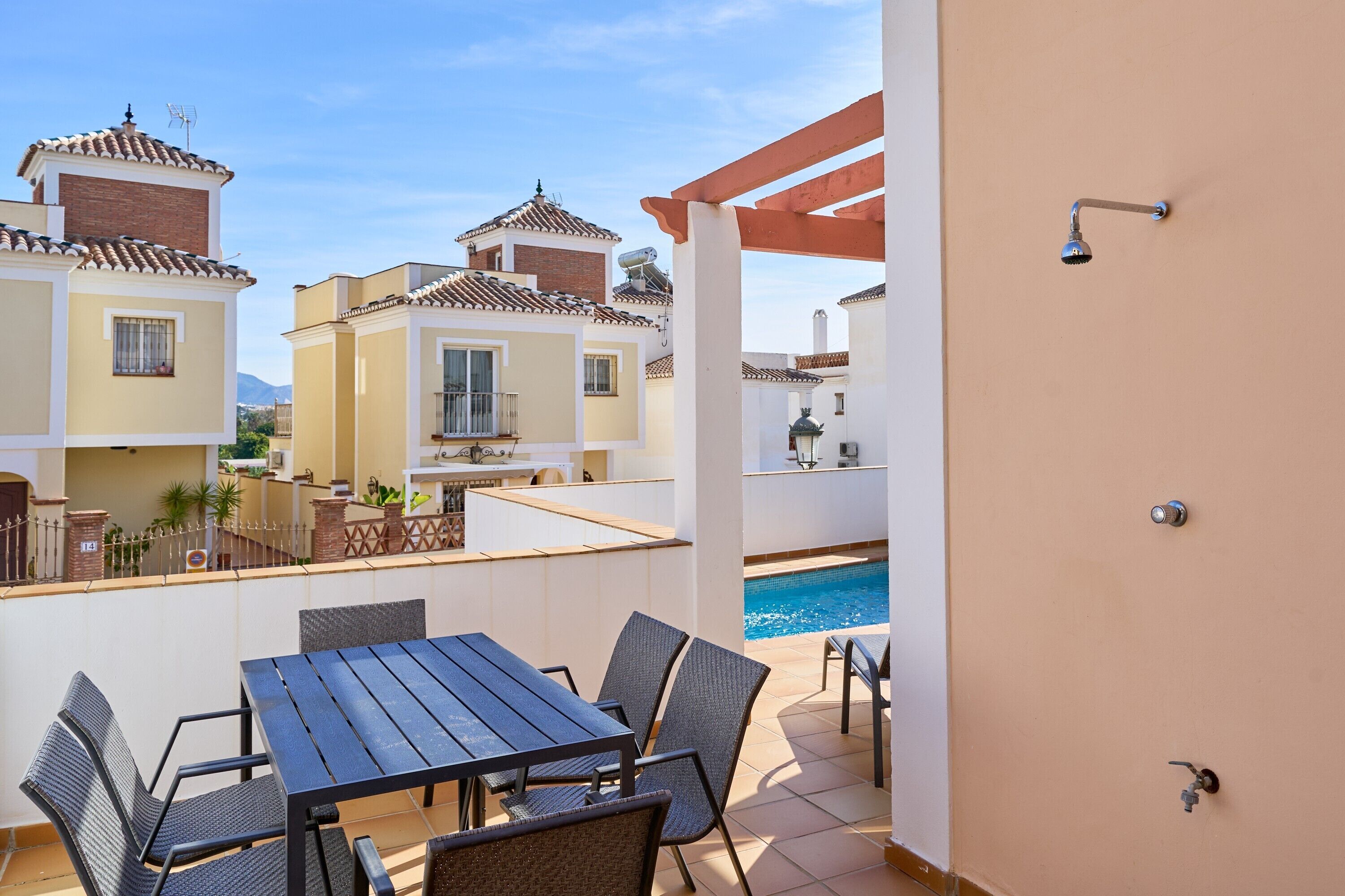 A balcony with a pool, outdoor seating, and a view of neighboring buildings.