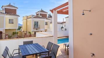 A balcony with a pool, outdoor seating, and a view of neighboring buildings.