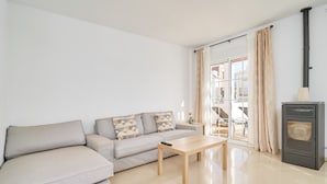 A living room with a sofa, a wooden coffee table, a fireplace, and a sliding glass door leading to an outdoor area. - Villa 'Bianca' with Sea Views, Wi-Fi, and Air Conditioning (Málaga)