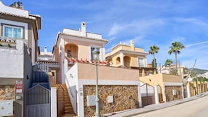 A residential building with a stone facade, a gated entrance, and a clear blue sky. - Villa 'Bianca' with Sea Views, Wi-Fi, and Air Conditioning (Málaga)