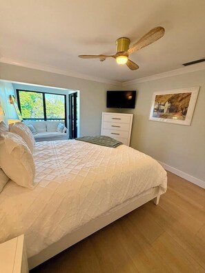 Ein Schlafzimmer mit einem Bett, einem Deckenventilator, einem Fernseher und einem Bild an der Wand.