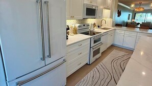 Een moderne keuken met witte kastjes, roestvrijstalen apparatuur en een vloerkleed met een herringbone patroon.