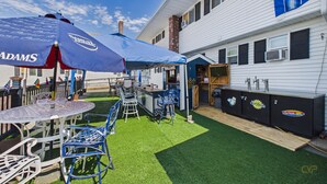 A patio area with a table, chairs, and a blue umbrella. - Rally Point Inn & Pub (Foxborough)