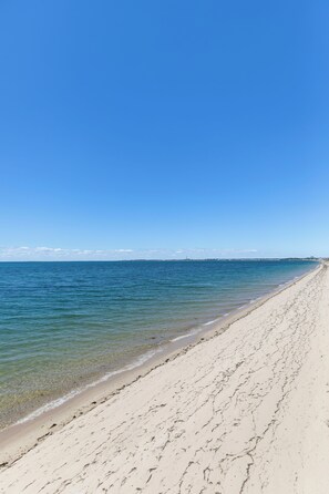 A beach with clear blue water and a sandy shore. - Private Beachfront Cottage for 2—Spacious Deck on the Water, Breathtaking Views! (Truro)