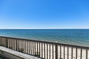 A wooden pier leading to a sandy beach with clear blue water.