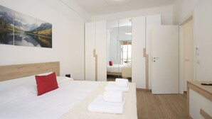 A modern hotel room with a large bed, a red pillow, a painting of a mountain landscape, and a mirror reflecting the room. - Domus Alexander by Ghor (Rome)