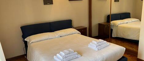 Une chambre d’hôtel avec un grand lit, deux tables de chevet et un miroir.