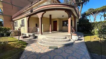 A building with a curved balcony, a covered entrance, and a patterned tile floor.