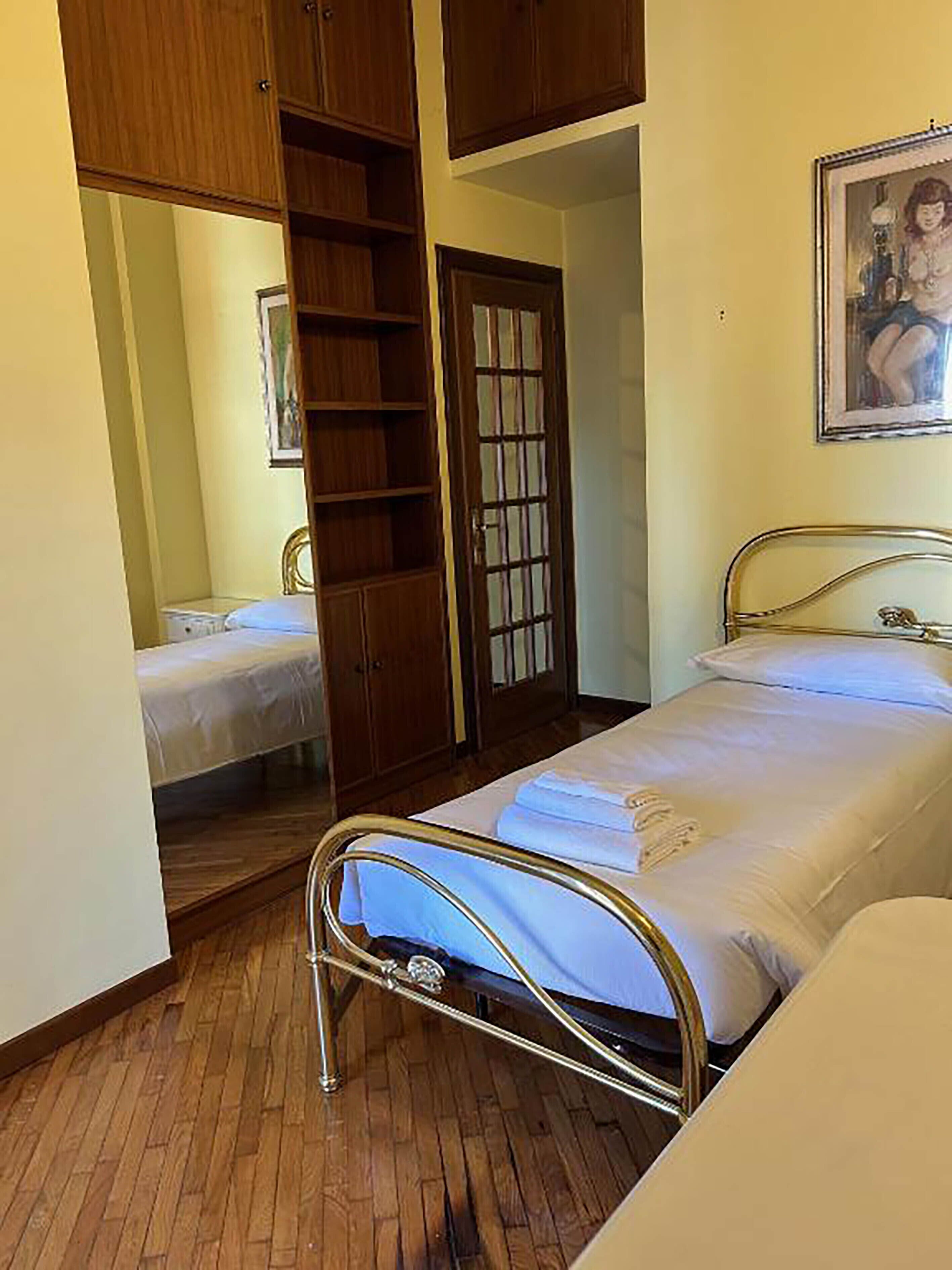 A bedroom with a bed, a wardrobe, and a mirror.