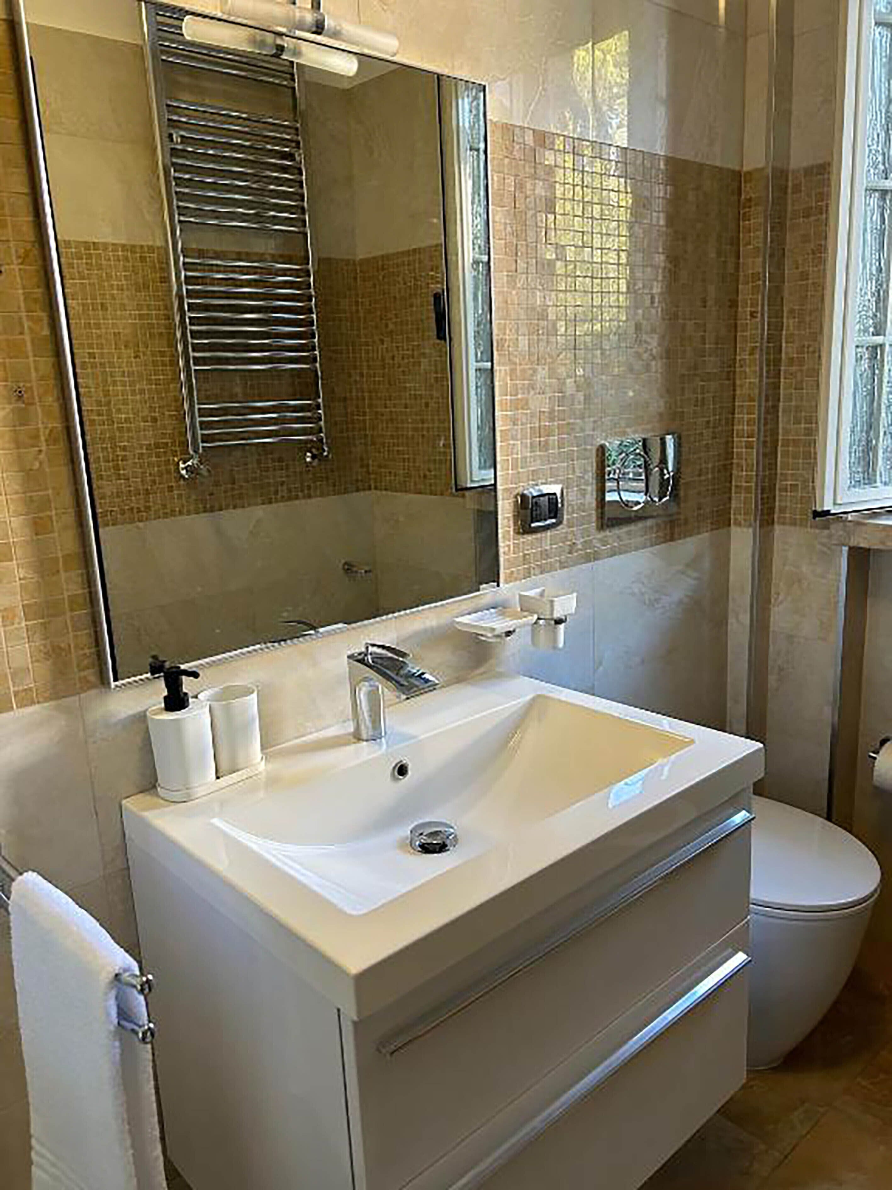 A bathroom with a white sink, a mirror, a towel rack, and a toilet.