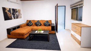 Una sala moderna con un sofá modular, una mesita de centro, un aparador y un cuadro en la pared.