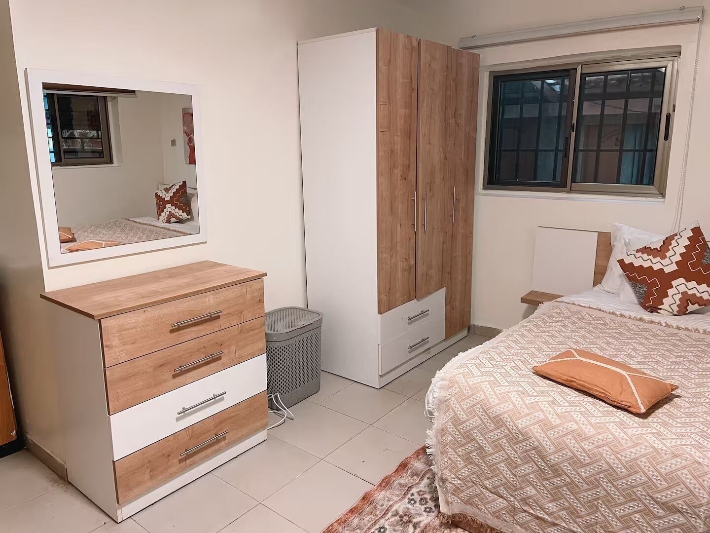 Un dormitorio con cama, cómoda, armario, espejo y ventana.