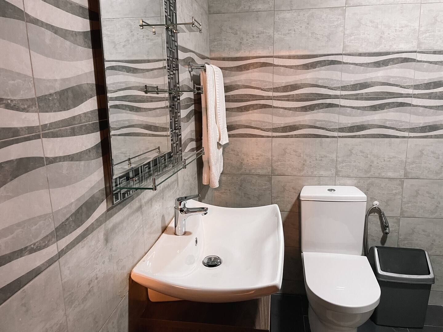 A bathroom with a white sink, a toilet, and a towel rack.