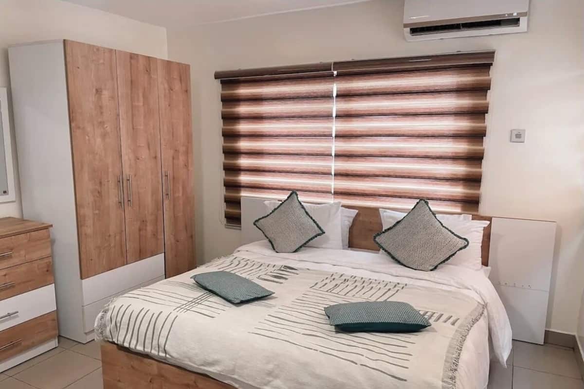 Ein Schlafzimmer mit Bett, Kleiderschrank und einem Fenster mit Jalousien.