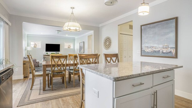 A modern kitchen with a granite countertop, wooden chairs, and a dining table. - Bridgewater Cottage- Close to Beach, 6 Bedrooms. (South Haven)
