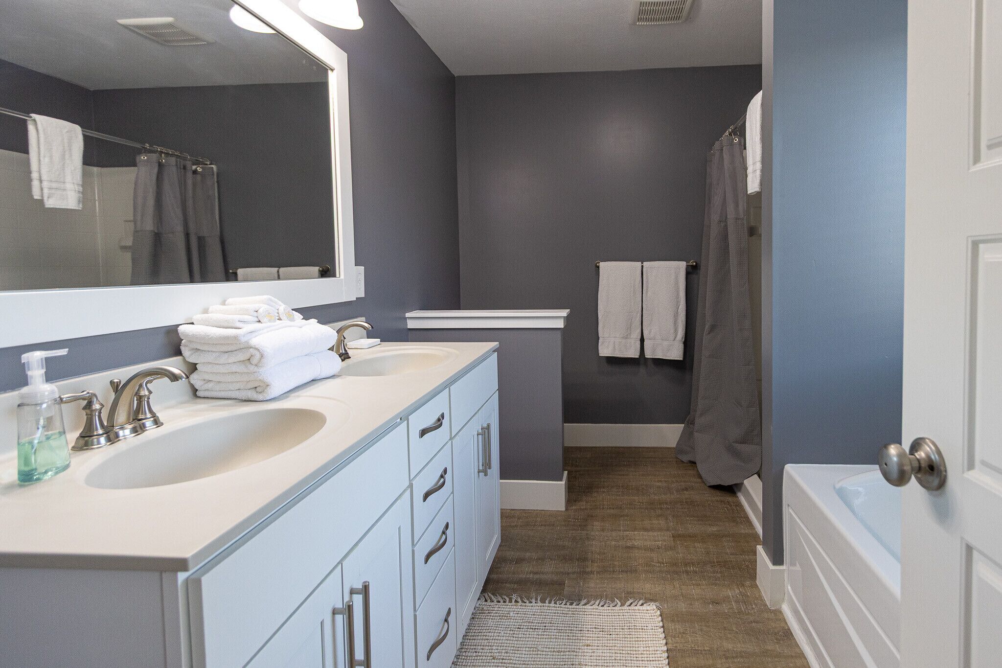 A modern bathroom with a large mirror, a sink, and a bathtub.
