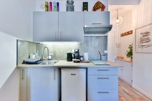 A modern kitchen with a built-in dishwasher, a coffee maker, and a sink. - Le Festif studio avec loggia au Carré d'Or (Cannes)