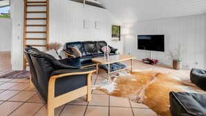 Ein modernes Wohnzimmer mit einer schwarzen Ledersofa, einem Holztisch und einem Kuhfellteppich.