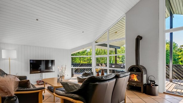 Ein modernes Wohnzimmer mit Kamin, großen Fenstern und einem Fernseher.