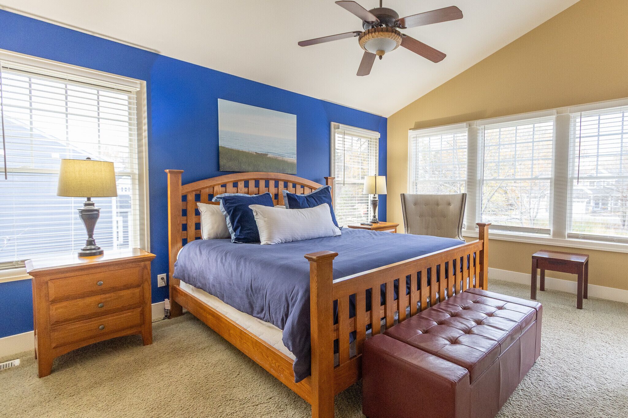 Primary bedroom with a plush king bed, bold accent wall. cozy seating, and access to private en-suite bathroom.