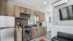 A modern kitchen with wooden cabinets, a built-in microwave, and a stainless steel oven. - Morning Glory - Floating Cottage (TFC#3) - Resort (South Haven)