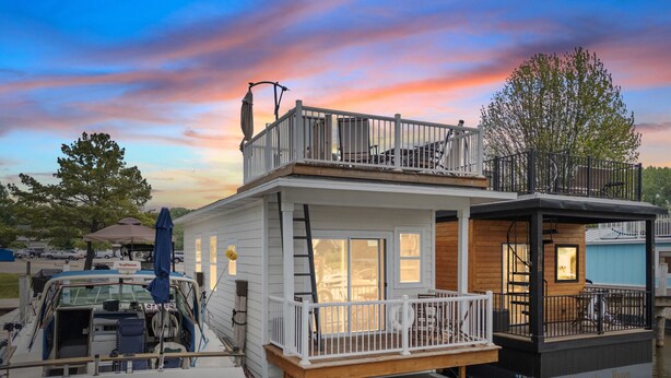 A houseboat with a wooden deck, a balcony, and a small porch area. - Morning Glory - Floating Cottage (TFC#3) - Resort (South Haven)