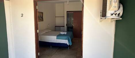 A room with a bed, a small desk, and a wall-mounted air conditioning unit.