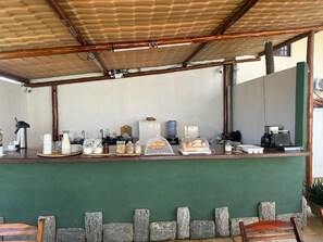 Egy fedett, szabadtéri terület, ahol egy pulton a reggelihez kínált ételek vannak kiállítva, emellett található itt egy kávéfőző és egy vizes adagoló is.