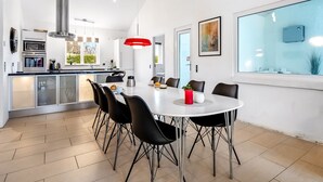 A modern kitchen with a central island, a dining area with a round table and chairs, and a large window providing a view. - "Synne" - 350m from the sea by Interhome (Grenaa)