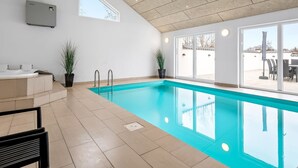 A modern indoor swimming pool with a clear view of the outside, a built-in hot tub, and a ceiling with recessed lighting. - "Synne" - 350m from the sea by Interhome (Grenaa)