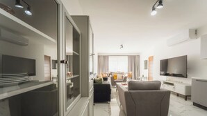 Una sala de estar moderna con un sofá, televisor y un comedor con mesa y sillas.